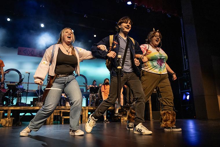 Three actors sing and walk across the stage during a production of The Lightning Thief: The Percy Jackson Musical